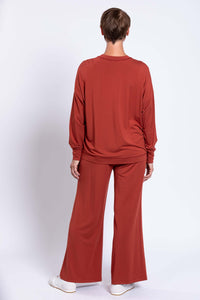 Back view of woman in relaxed fit rust bamboo crew neck top and pants