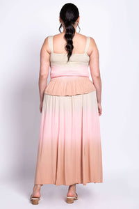 Back view of a woman wearing a maxi dress with beige, pink, and peach ombre gradient