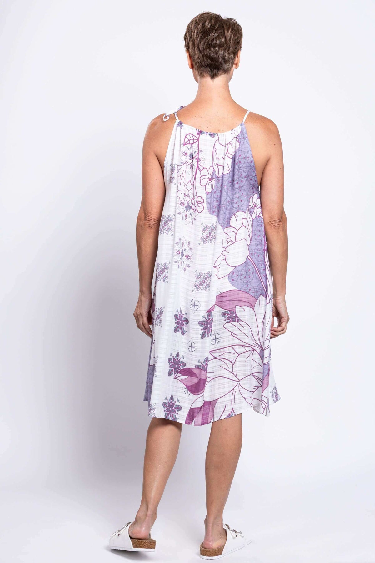 Back view of a woman in a purple and white floral sleeveless knee-length summer dress