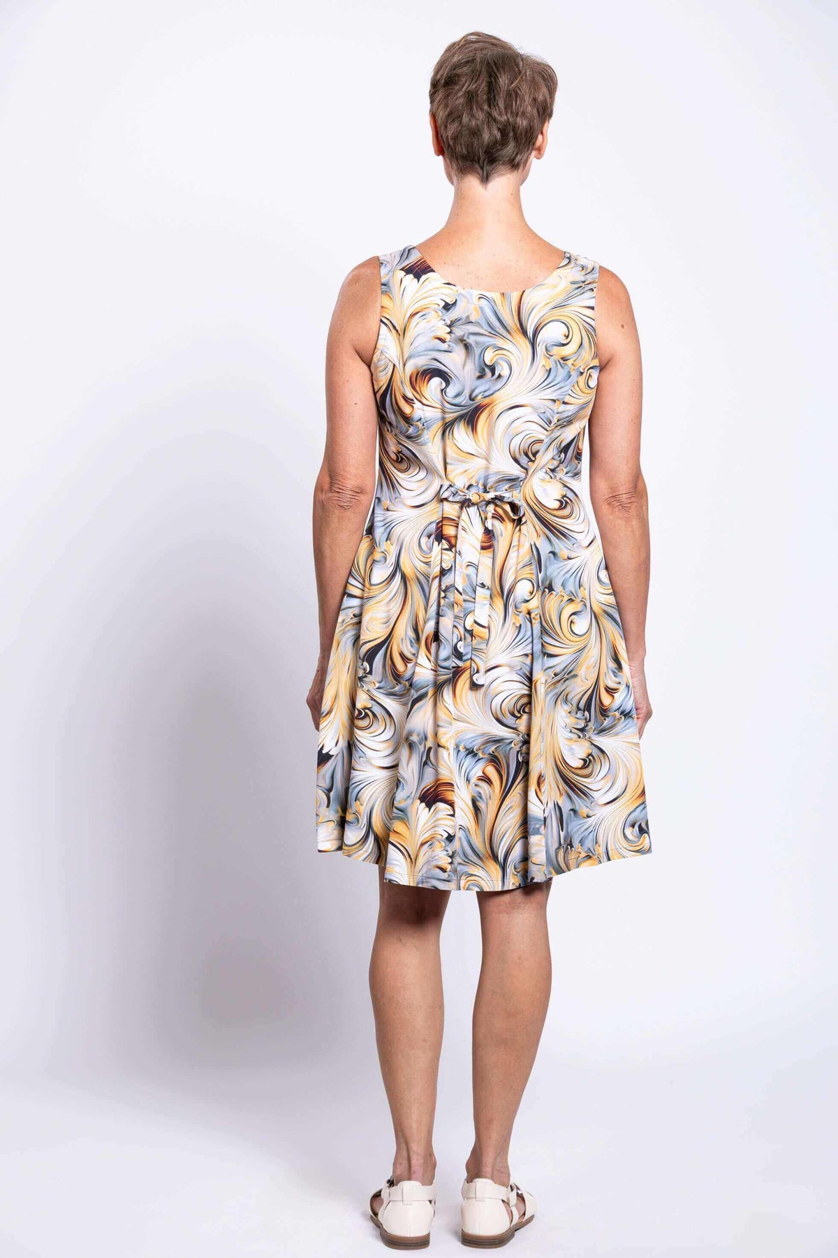 Back view of older woman in sleeveless swirl print dress with tie waist
