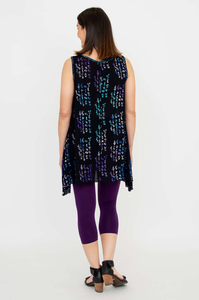Back view of model in black swing tank top with purple and teal script pattern and elongated sides