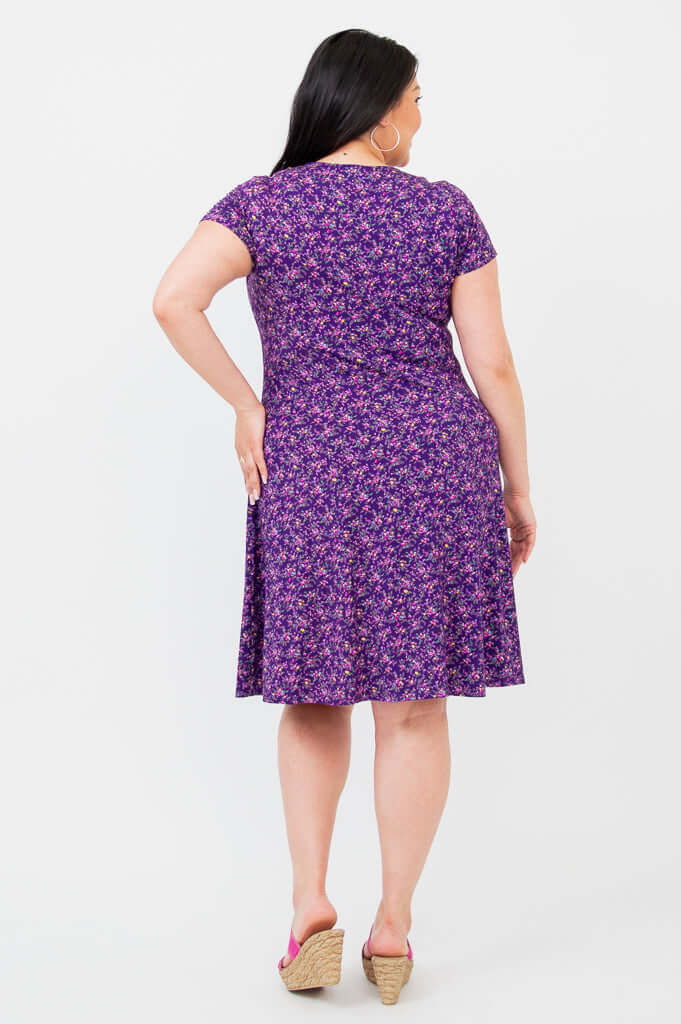 Back view of woman wearing a purple floral short-sleeve dress with A-line silhouette