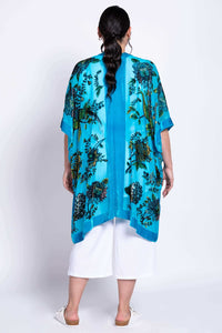 Back view of model wearing a turquoise kimono wrap with intricate floral prints