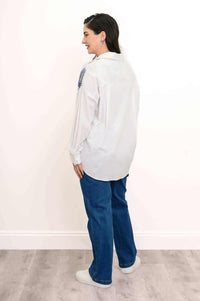 Back view of woman wearing white blouse with subtle blue and gold floral touches