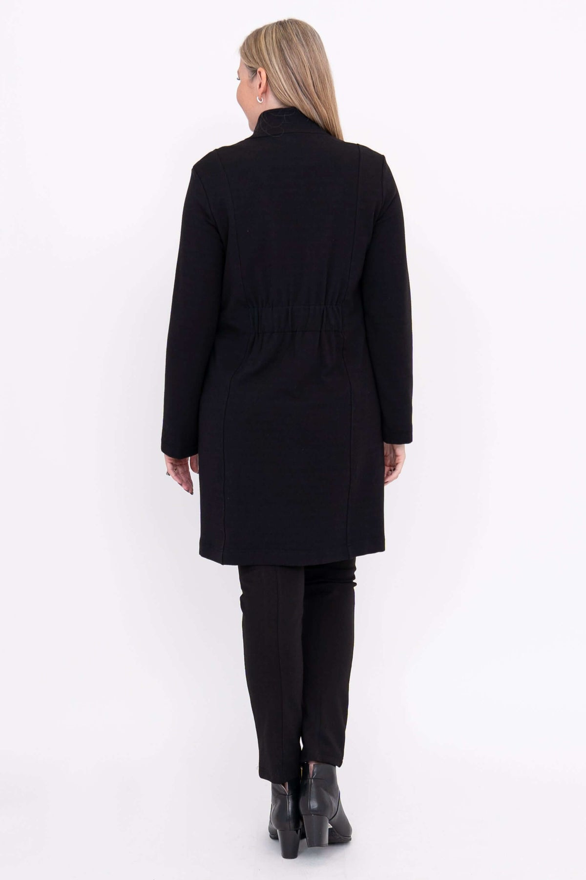 Back view of woman in black cotton mid-length coat with elastic waist detail