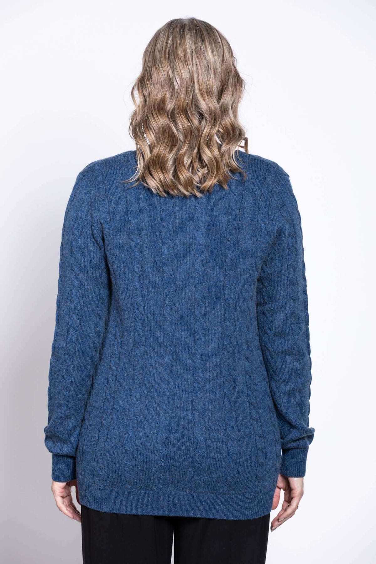 Back view of woman in blue cable knit button-up cardigan