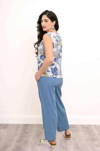 Woman showing back of blue and yellow floral sleeveless tank top with blue pants