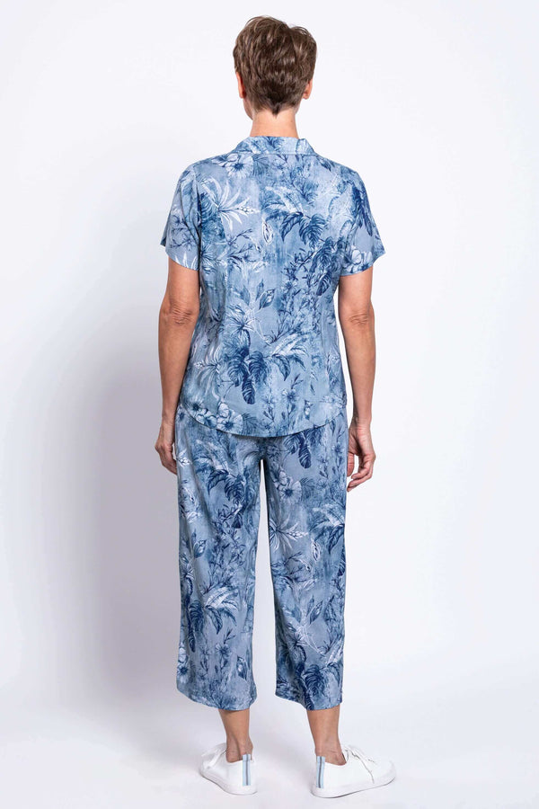 Woman wearing a blue floral short-sleeve shirt and pants, back view