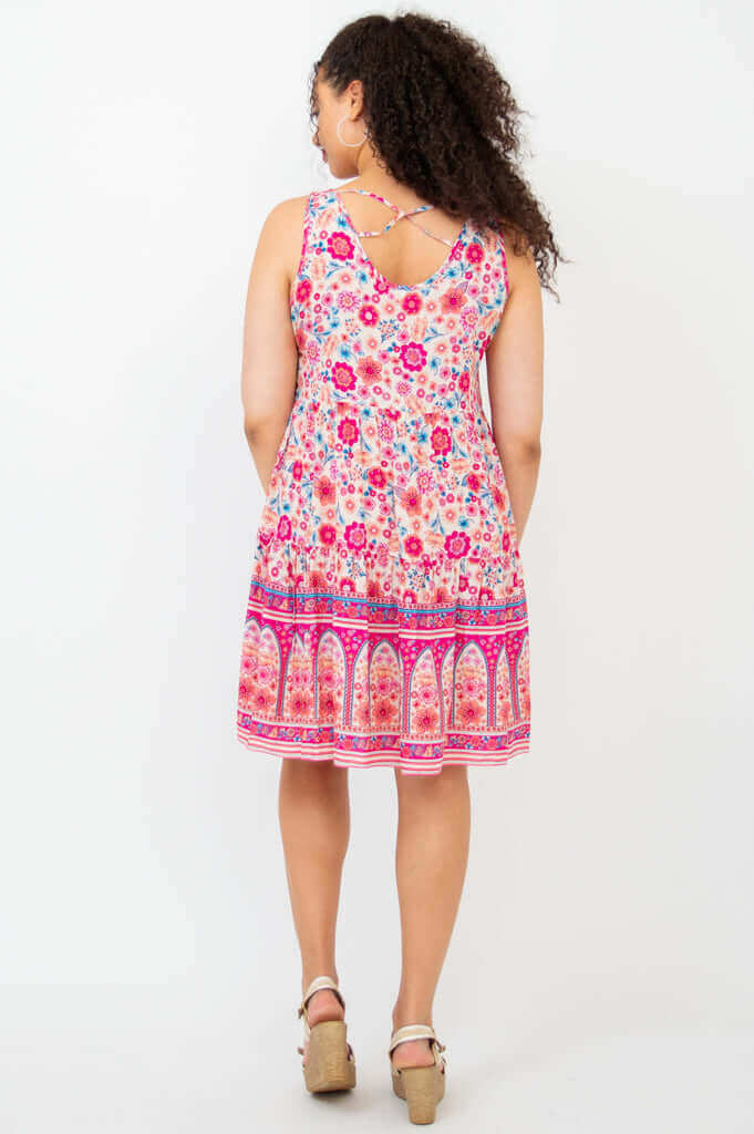 Back view of woman wearing sleeveless dress with crisscross detail and floral pattern.