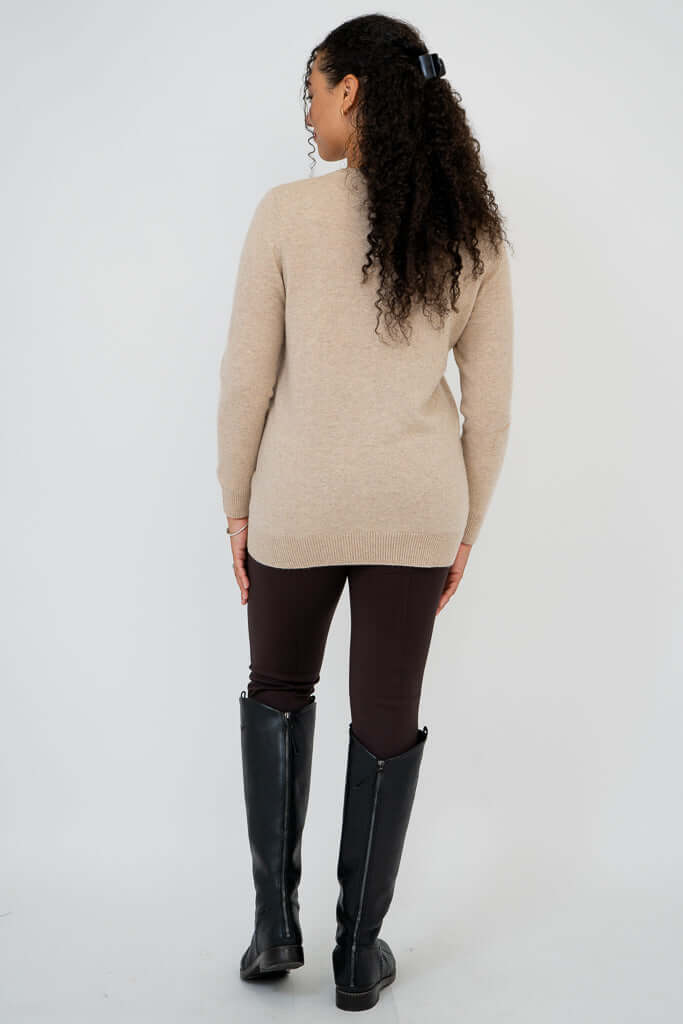 Back view of woman wearing beige sweater and brown pants with boots