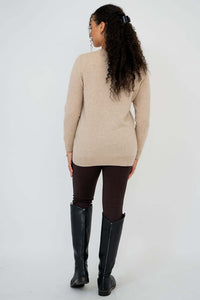 Back view of woman wearing beige sweater and brown pants with boots