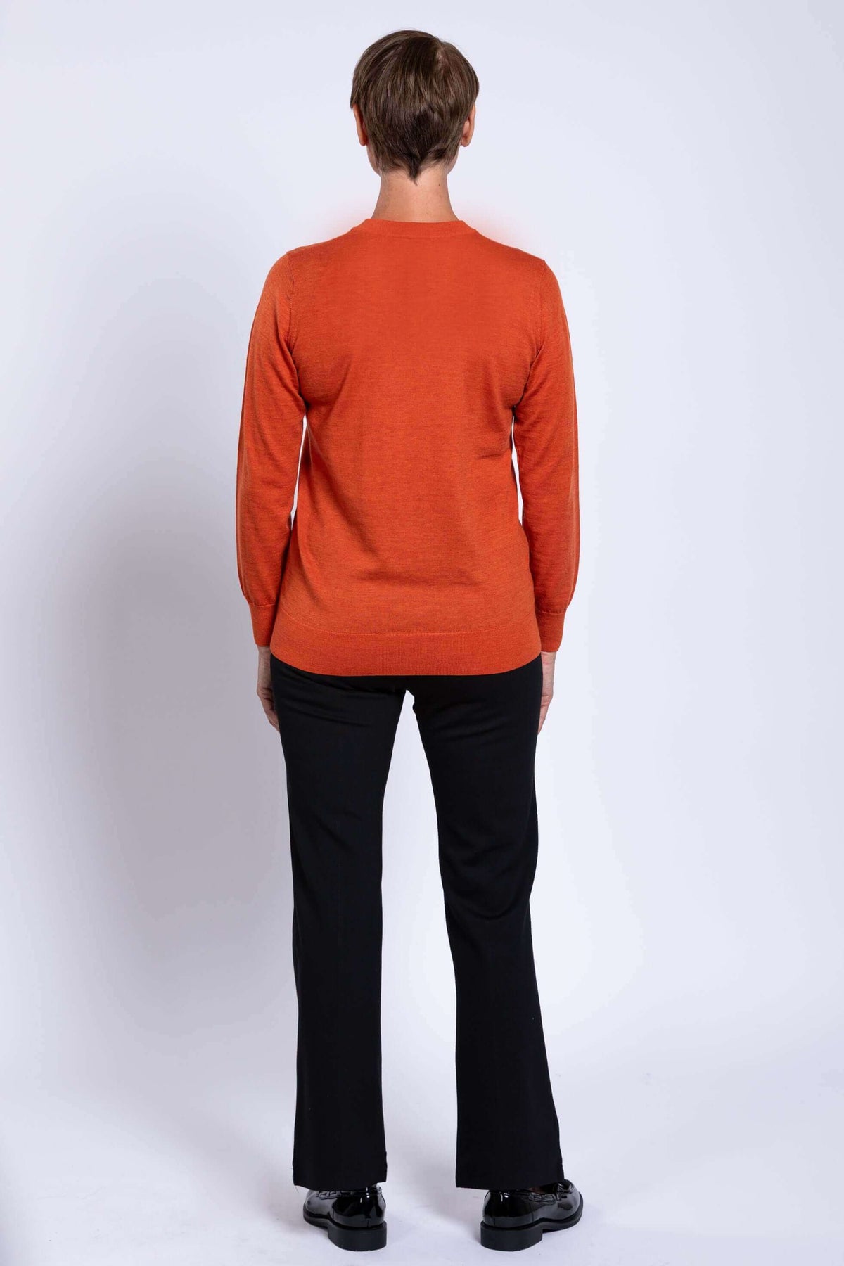 Back view of woman wearing the orange V-neck merino wool sweater