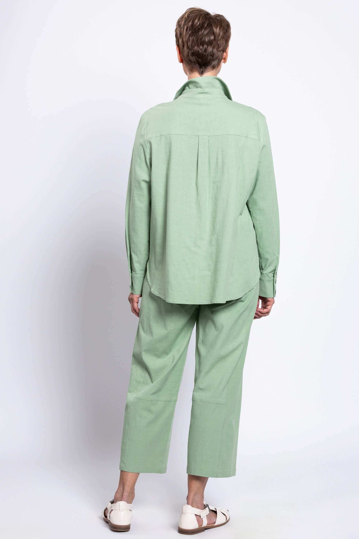 Rear view of a woman in a sage green shirt and matching pants, showing shirt back