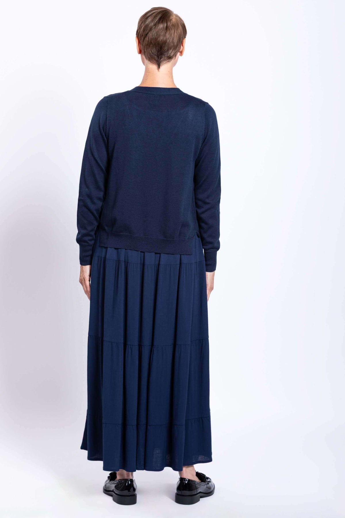 Back view showing navy Roma tiered maxi skirt and sweater, hands by sides
