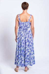 Back view of a woman in a blue paisley maxi dress showing shirred bodice and belt
