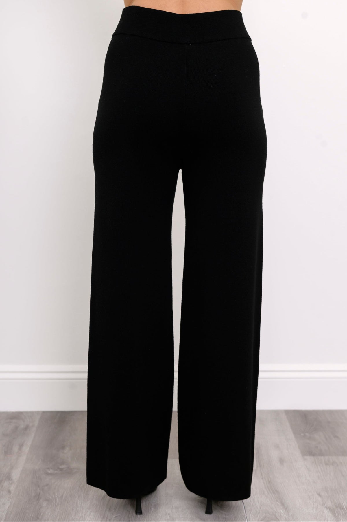 Rear view of a model in black straight-leg trousers, showcasing a comfortable mid-hip rise and fluid fall.