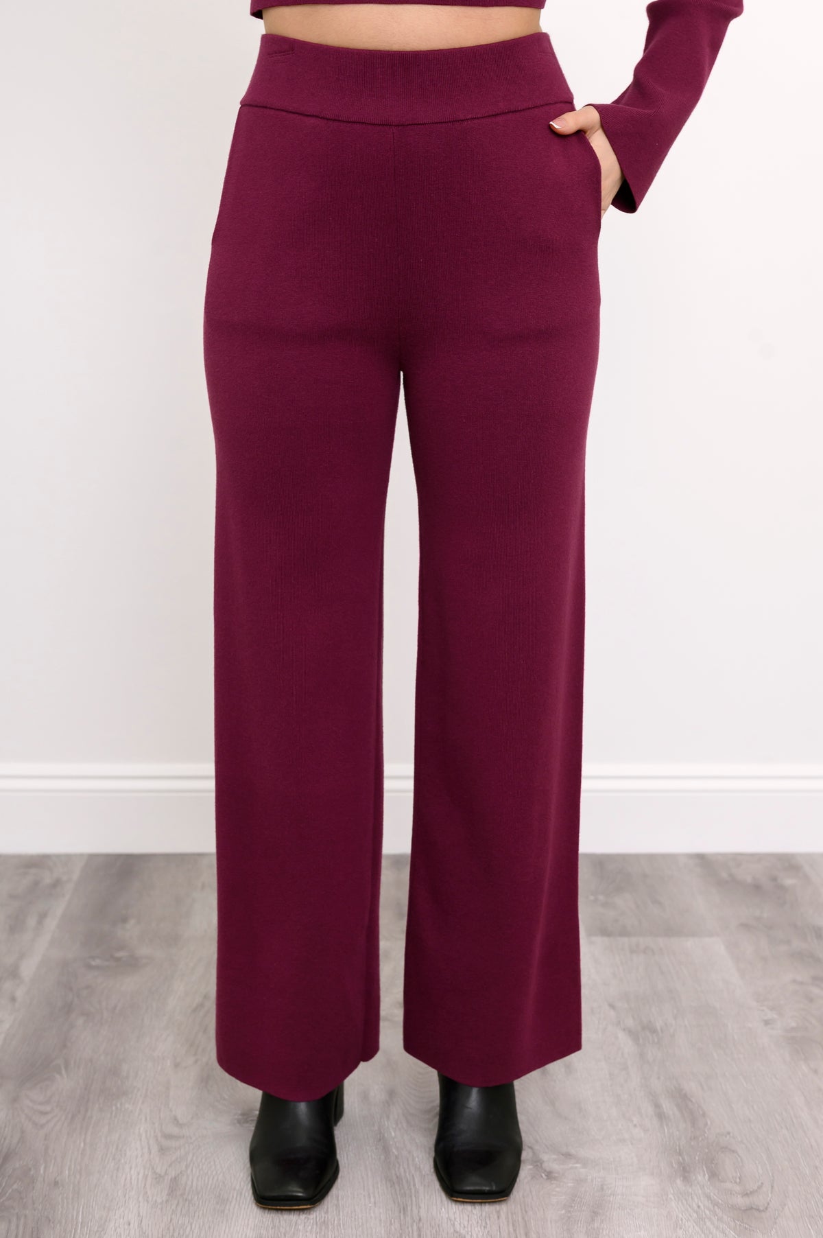 Close-up front view of women's relaxed-fit maroon track trousers, highlighting the straight-leg silhouette.