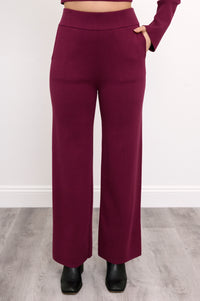 Close-up front view of women's relaxed-fit maroon track trousers, highlighting the straight-leg silhouette.