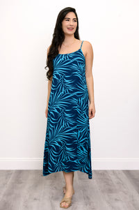 Front view of woman wearing a blue leaf-patterned dress and beige sandals against a white background
