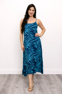 Front view of woman wearing a blue leaf-patterned dress and beige sandals against a white background