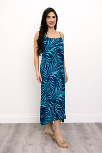 Side view of woman wearing a blue leaf-patterned dress and beige sandals against a white background