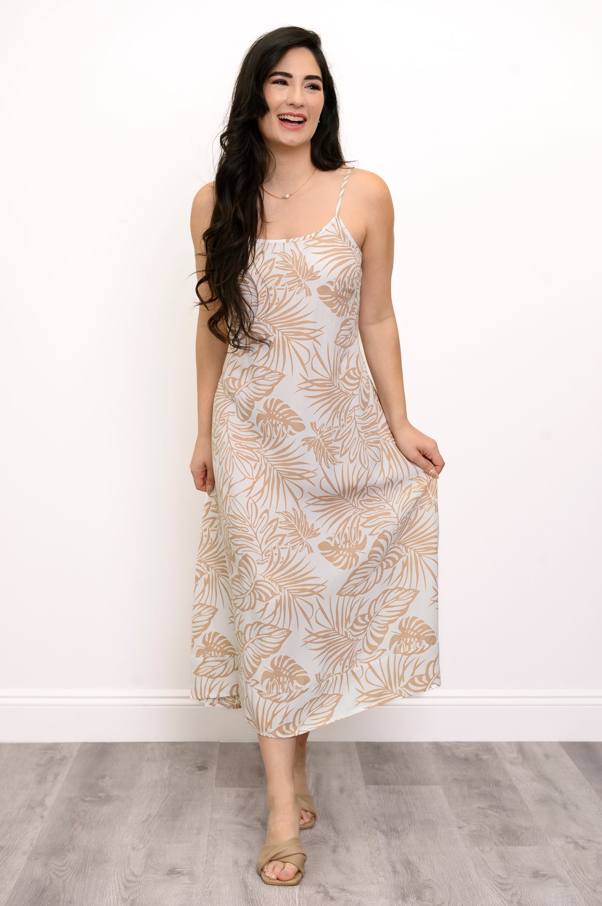 Front view of woman wearing a white and beige leaf-patterned dress against a white background