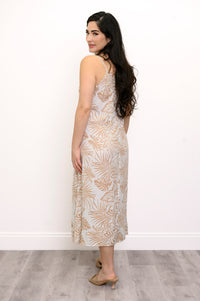 Back view of woman wearing a white and beige leaf-patterned dress against a white background