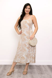 Front view of woman wearing a white and beige leaf-patterned dress and white bag against a white background