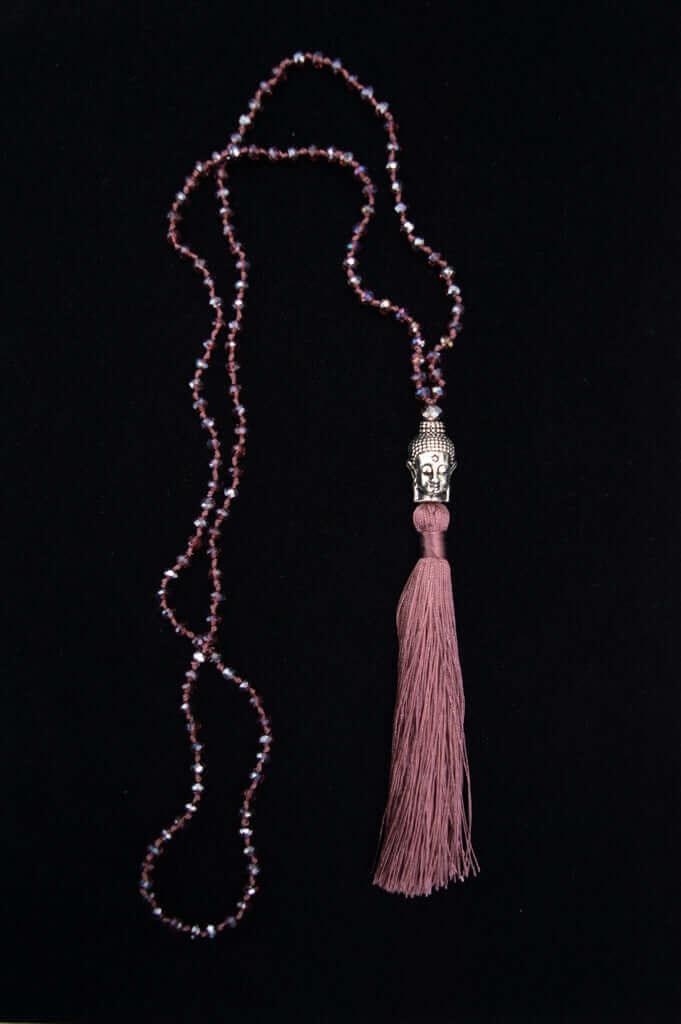 Beaded mala necklace with Buddha head accent and matching tassel against a black background