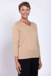 Woman wearing a beige V-neck cotton sweater with black pants, facing forward