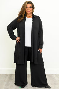 Woman wearing a black structured long tunic top with a front button placket over a white shirt and black pants