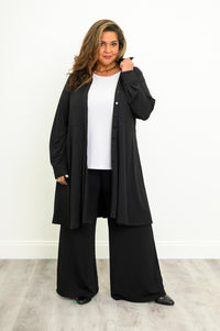 Front full-length view of a casual black long sleeve tunic top with an empire waistline and skirted bottom.