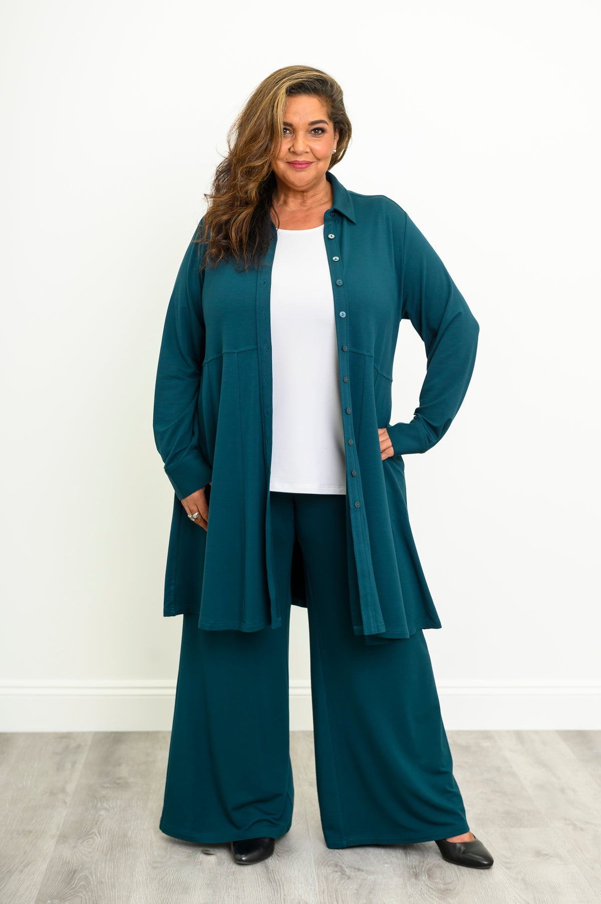 Straight-on full body portrait of a women's teal long-line shirt styled open as a light jacket.