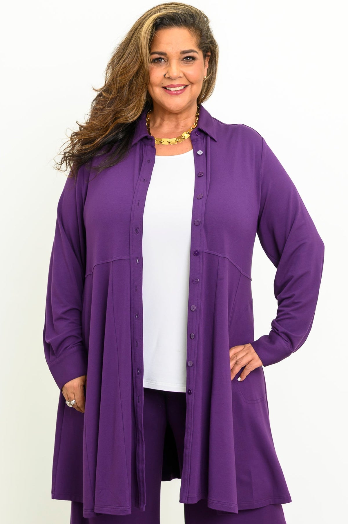 Front view of a smiling woman wearing an open royale purple bamboo French terry tunic layered over a white top.