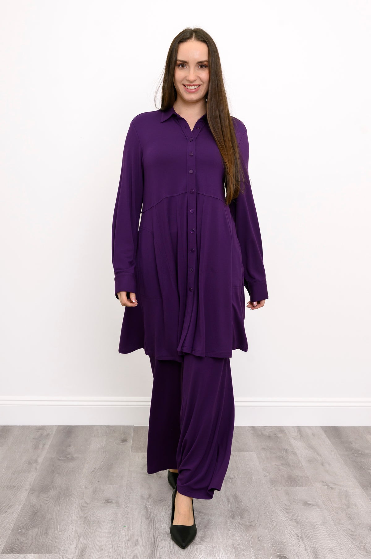 Wide studio shot of a loose-fit purple bamboo tunic featuring an empire waistline and paneled skirt layout.