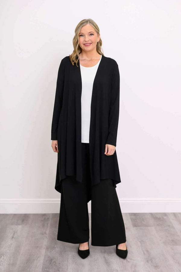 Front view of model in black high-low duster cardigan with white top and black pants