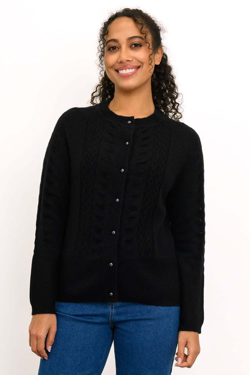 Woman wearing a black cable knit cashmere cardigan with pearl buttons, front view