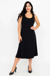 Woman wearing a sleeveless black A-line dress with scoop neckline, standing indoors