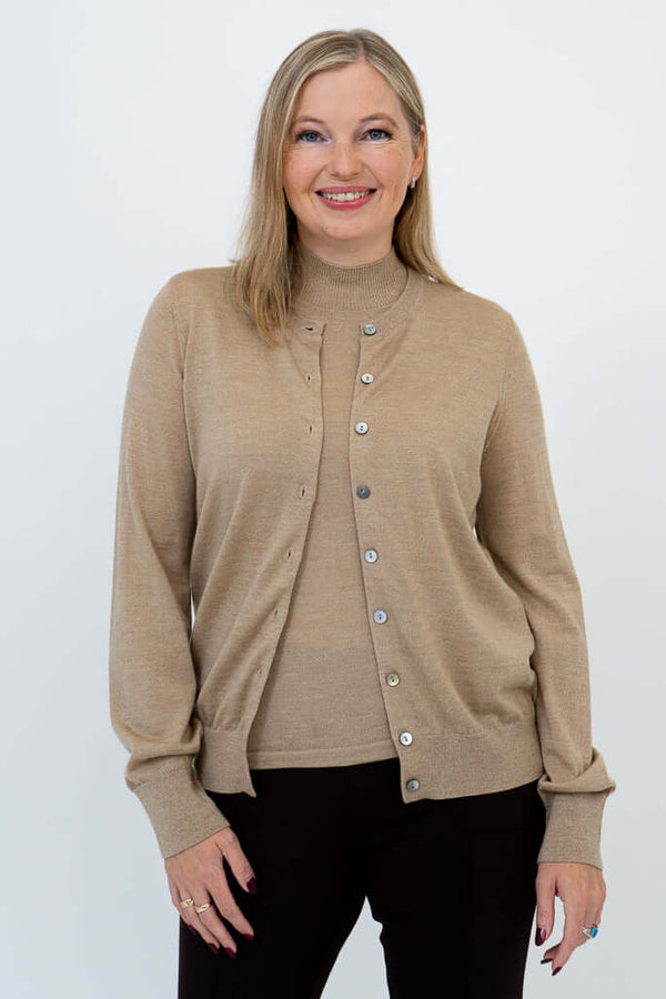 Smiling woman with blonde hair in tan Merino wool cardigan and brown pants