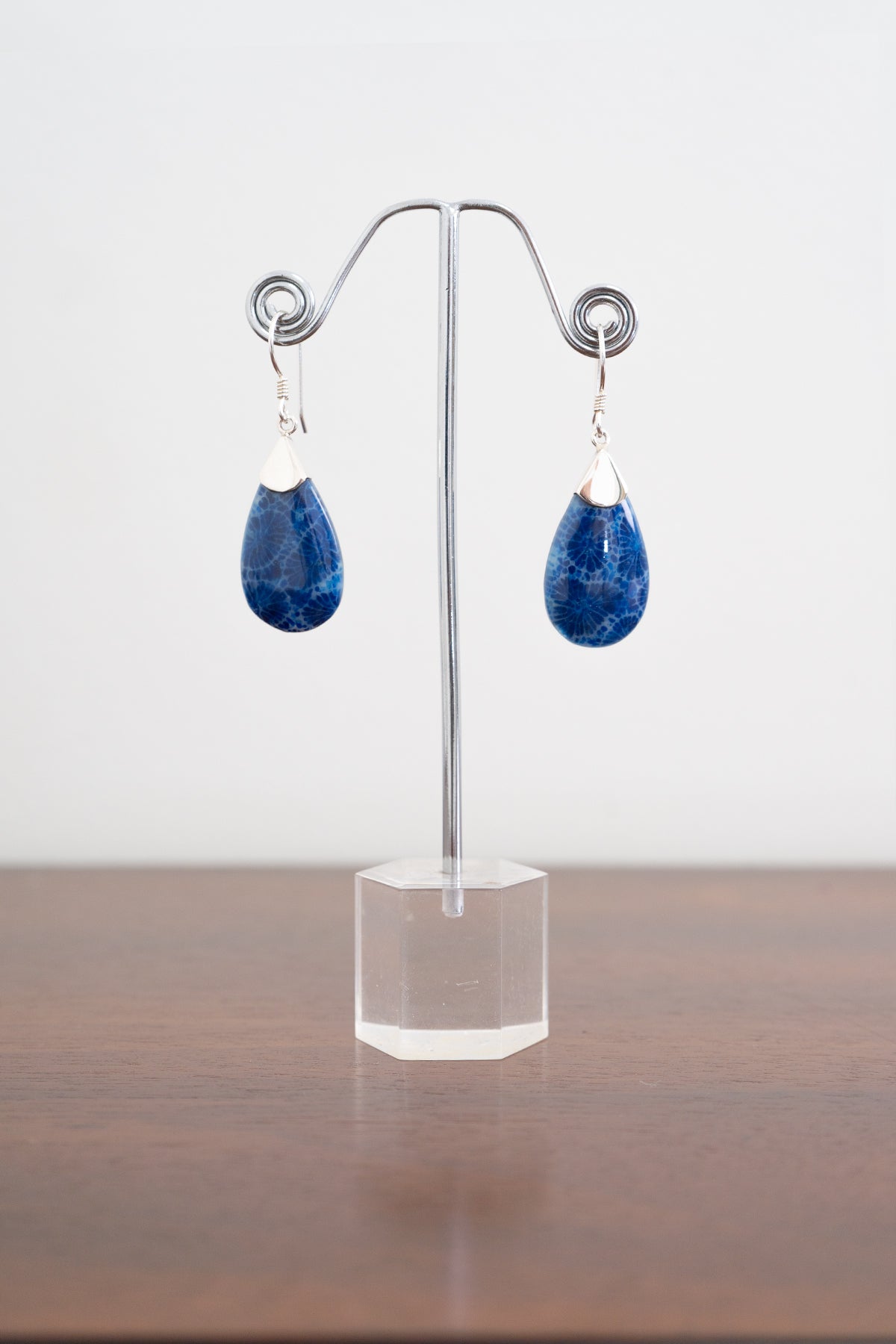 Front view of sterling silver marbled blue teardrop earrings on a clear stand against a white background
