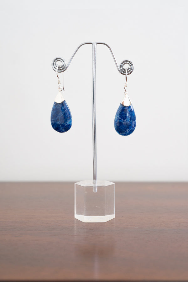 Front view of sterling silver marbled blue teardrop earrings on a clear stand against a white background