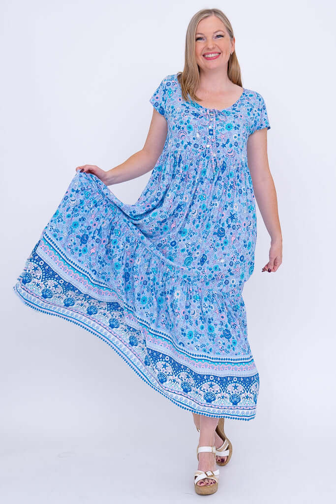 Woman holding skirt of blue boho maxi dress to show flowy, tiered design