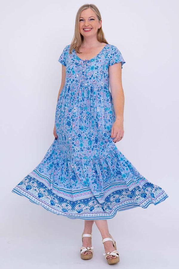 Woman swirling in blue boho maxi dress with tiered skirt, front view