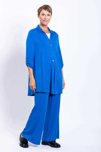 Woman in a blue French terry blouse with tab sleeves, standing at an angle