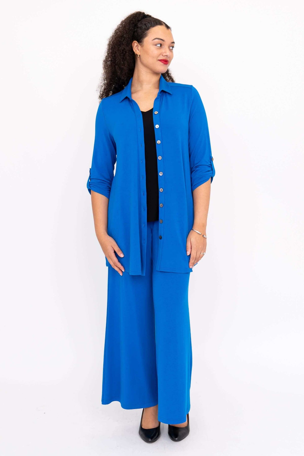 Woman in blue blouse-jacket and matching wide-leg pants with black top