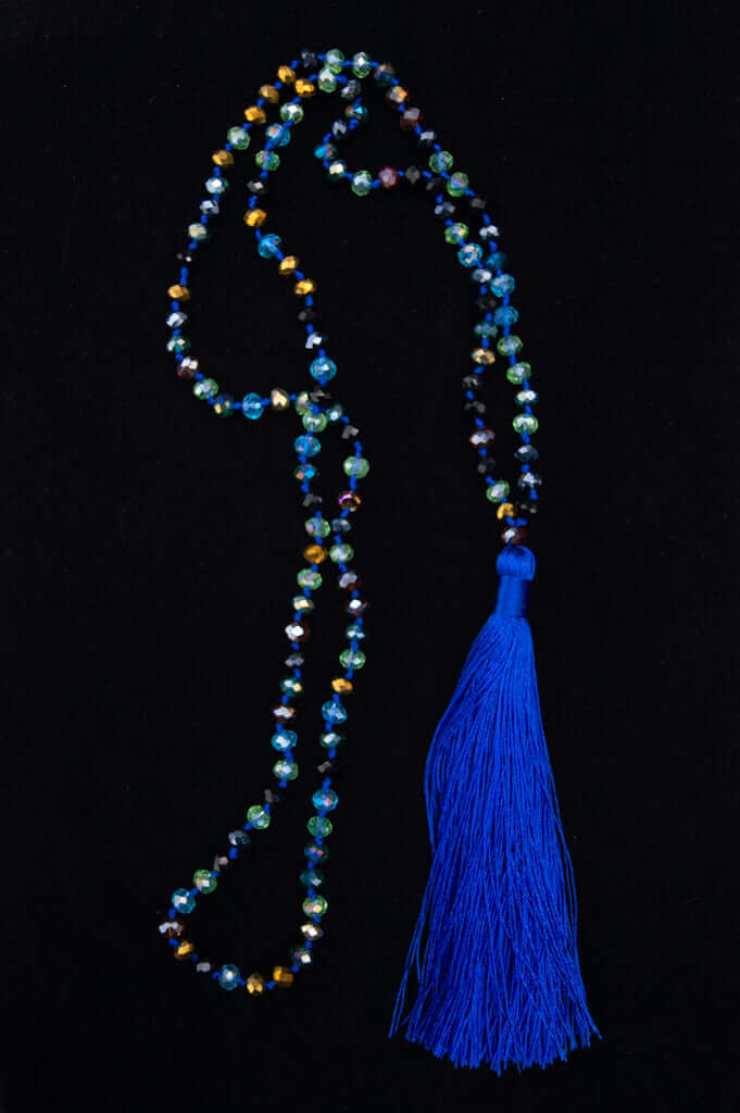 Faceted blue and multicolor crystal mala necklace with bold blue tassel on a black background