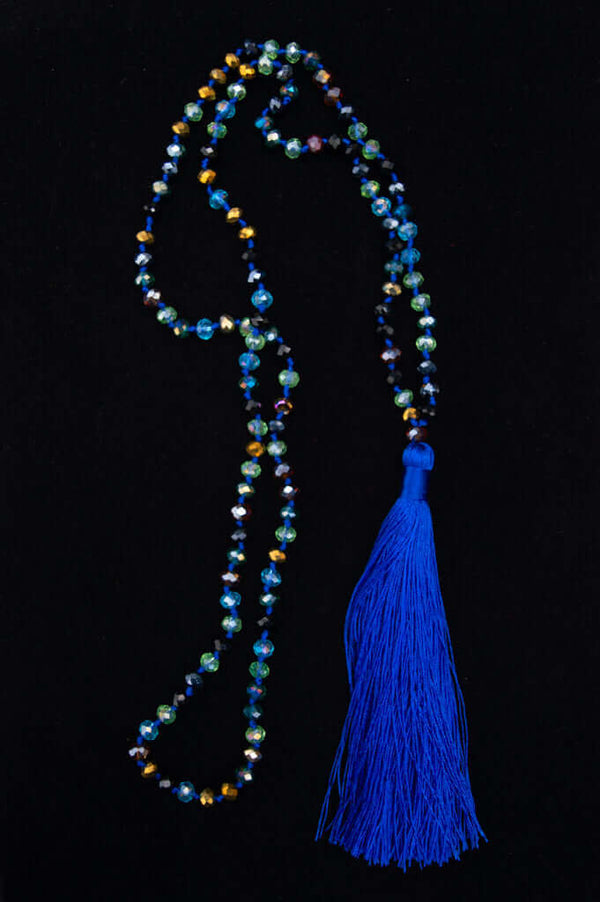 Faceted blue and multicolor crystal mala necklace with bold blue tassel on a black background