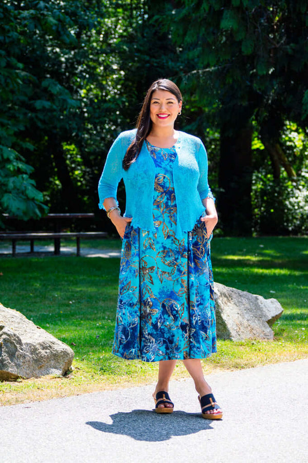 Model outdoors in a blue floral A-line midi dress with a blue cardigan