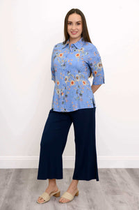 Model wearing a blue floral blouse and navy wide-leg pants, slight side pose