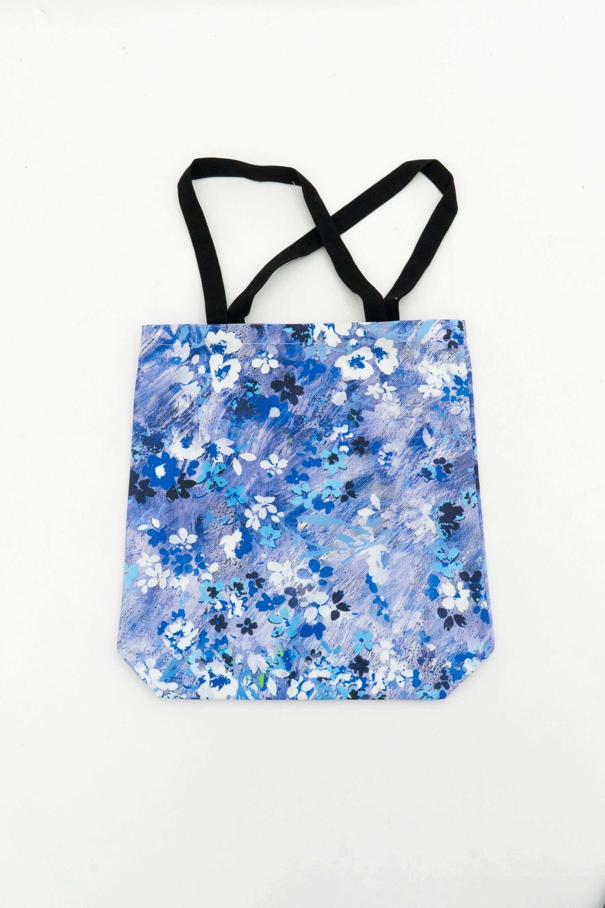 Reusable cotton canvas tote bag with blue floral pattern and black handles